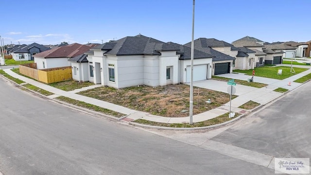 view of front of home featuring a garage, fence, concrete driveway, a residential view, and stucco siding