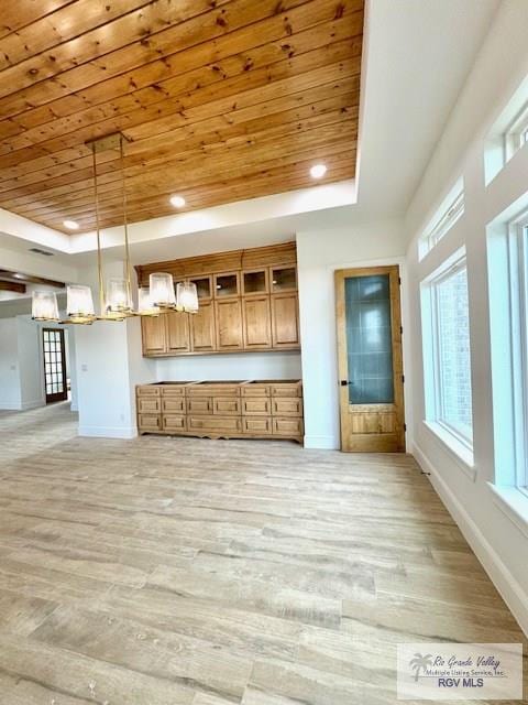 kitchen featuring a raised ceiling, wood ceiling, and decorative light fixtures