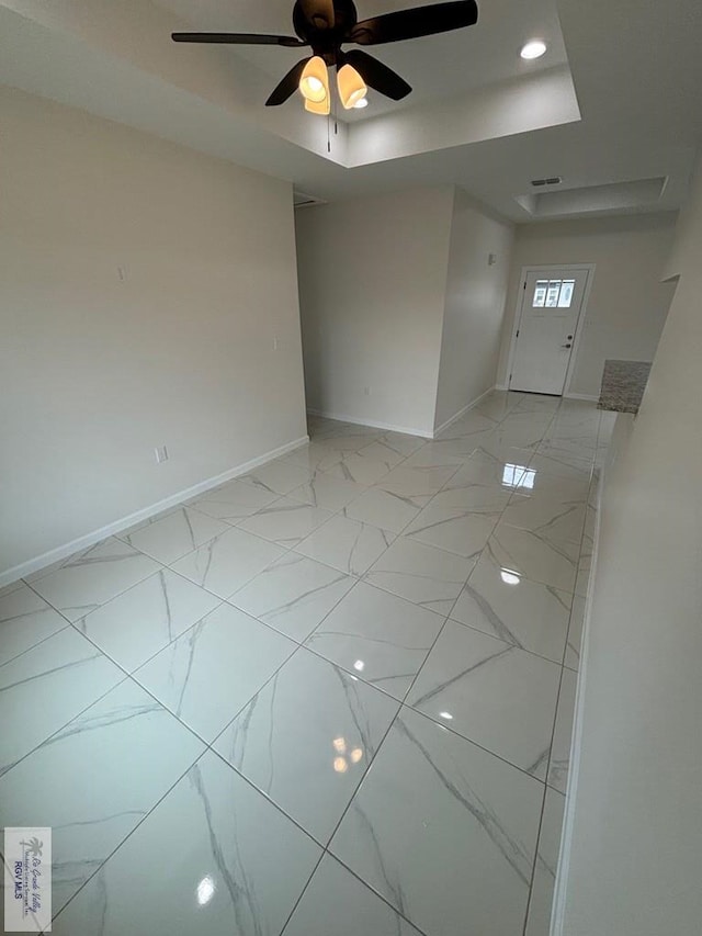 empty room with a tray ceiling and ceiling fan