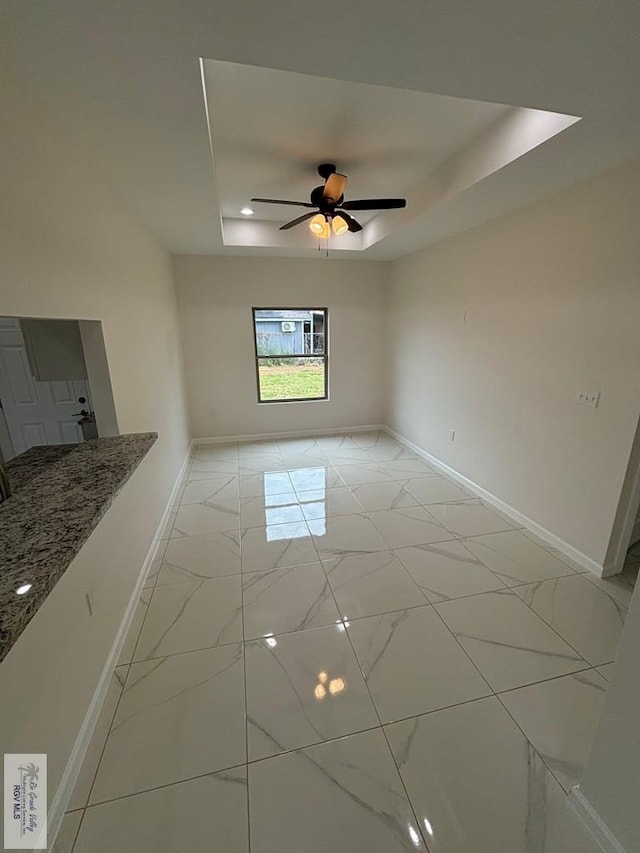 empty room featuring a raised ceiling and ceiling fan