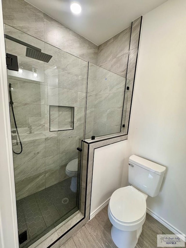 bathroom with toilet, wood-type flooring, and tiled shower