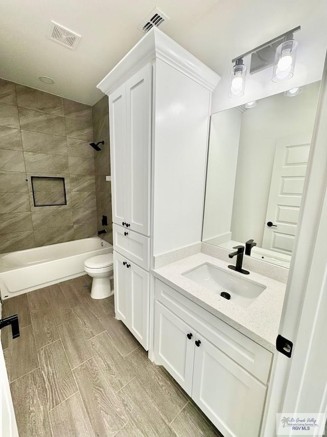 full bathroom with vanity, tiled shower / bath combo, and toilet