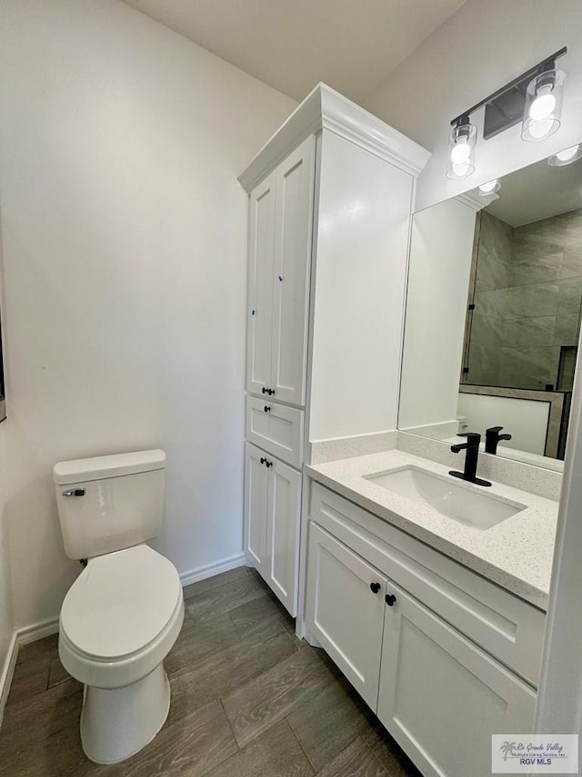 bathroom with tiled shower, wood-type flooring, vanity, and toilet