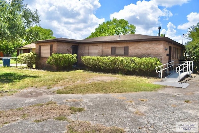 view of property exterior with a yard, brick siding, and fence