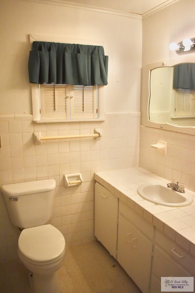 bathroom with vanity, ornamental molding, tile walls, and toilet