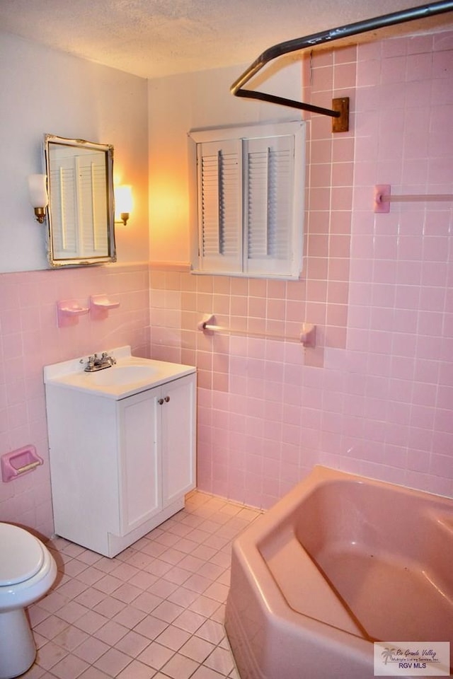 bathroom featuring vanity, tile patterned floors, toilet, tile walls, and a textured ceiling