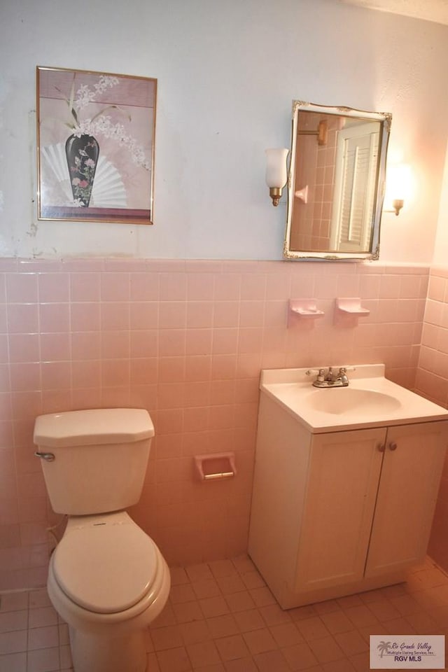 bathroom featuring vanity, toilet, and tile walls