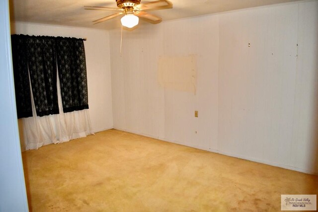 spare room with a ceiling fan and carpet