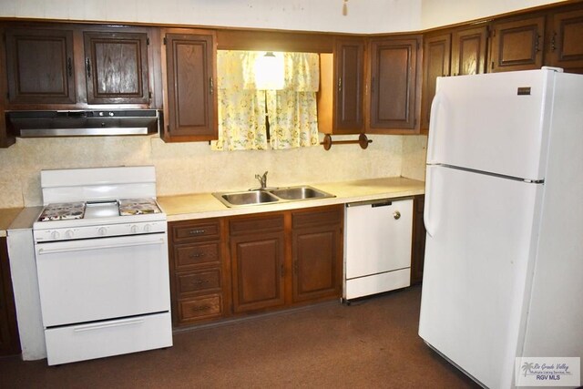 kitchen with under cabinet range hood, white appliances, light countertops, and a sink