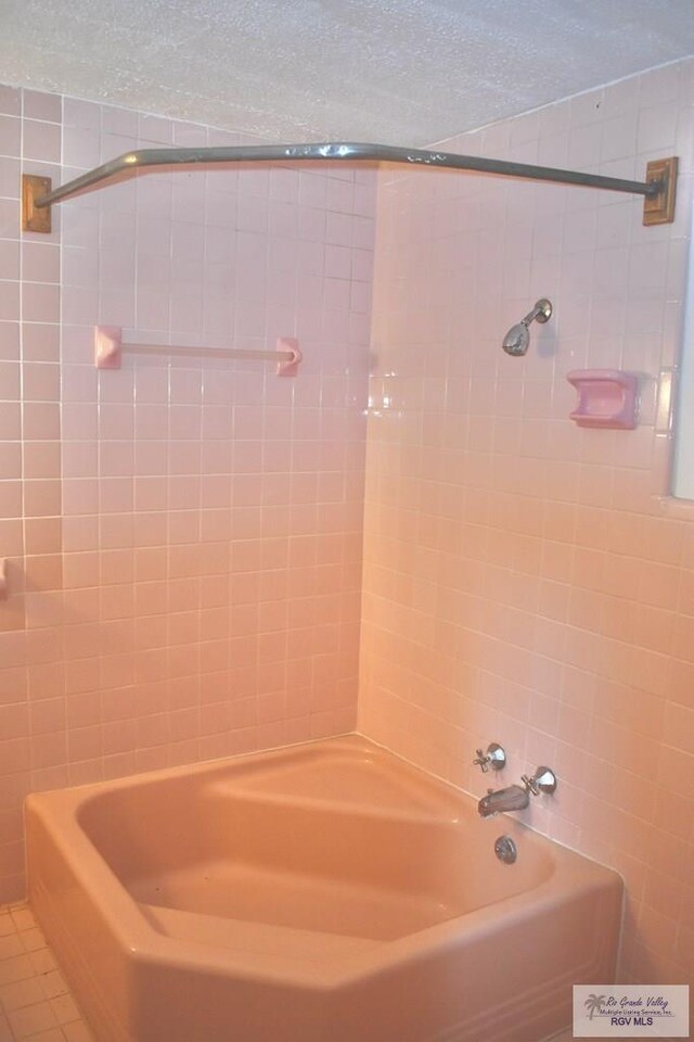 bathroom with tile patterned floors, washtub / shower combination, and a textured ceiling