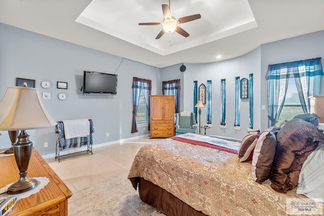 bedroom with light tile patterned floors, a raised ceiling, and ceiling fan