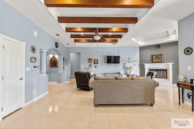 living room featuring light tile patterned floors, decorative columns, beamed ceiling, and ceiling fan