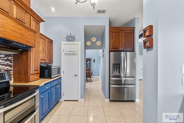 kitchen featuring light tile patterned flooring, decorative backsplash, stainless steel appliances, light stone countertops, and custom range hood