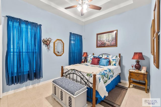 bedroom featuring light tile patterned floors, a tray ceiling, and ceiling fan