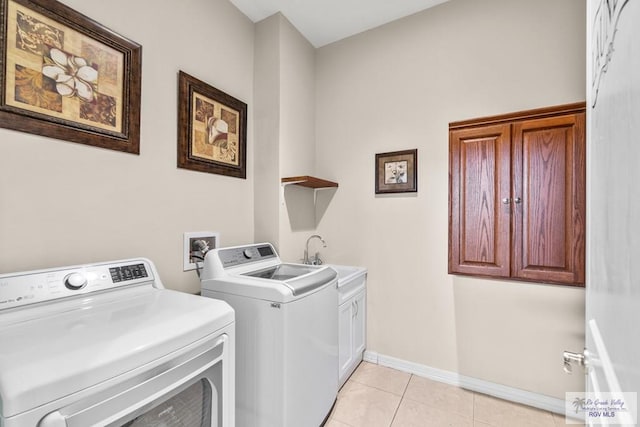 washroom with cabinets, light tile patterned flooring, sink, and washer and clothes dryer