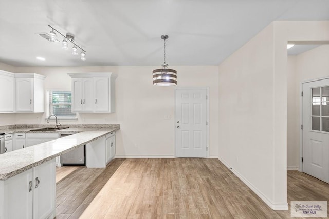 kitchen featuring sink, pendant lighting, a chandelier, white cabinets, and light hardwood / wood-style floors