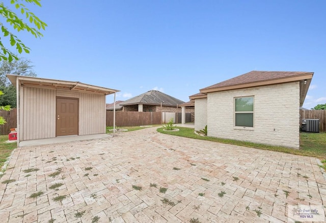 exterior space with central air condition unit, a patio, and a storage shed