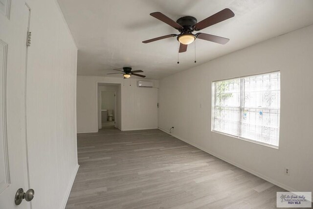 spare room featuring ceiling fan, light hardwood / wood-style floors, and a wall mounted air conditioner