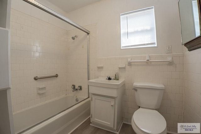 full bathroom with vanity, tiled shower / bath combo, wood-type flooring, tile walls, and toilet