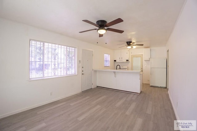 kitchen featuring ceiling fan, light hardwood / wood-style flooring, kitchen peninsula, white appliances, and white cabinets