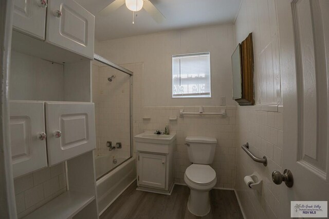 full bathroom featuring vanity, toilet, enclosed tub / shower combo, tile walls, and wood-type flooring