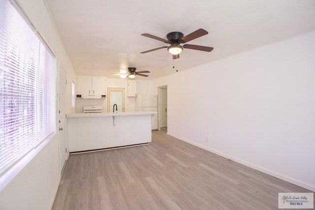 unfurnished living room with ceiling fan, light wood-type flooring, and sink