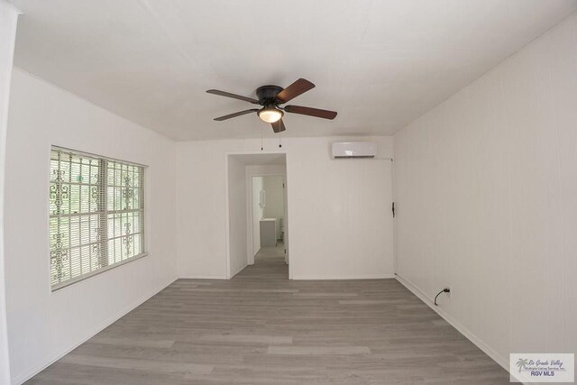 empty room with a wall unit AC, ceiling fan, and light hardwood / wood-style flooring