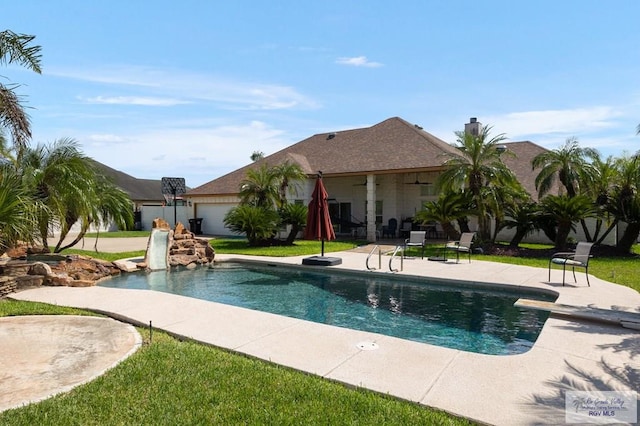 view of pool featuring a patio, a lawn, a diving board, and a water slide