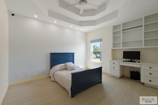 bedroom featuring a tray ceiling, ceiling fan, and light hardwood / wood-style floors