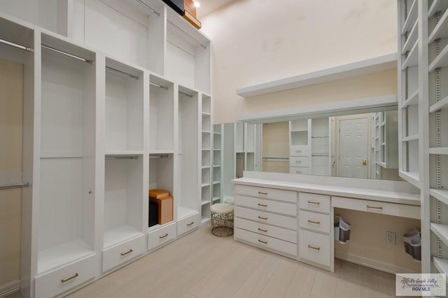 spacious closet featuring light wood-type flooring and built in desk