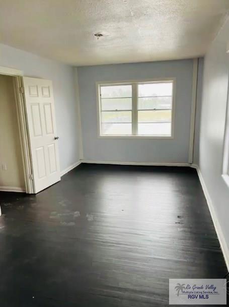 2605 Wilson Rd, Harlingen, TX 78552 - unfurnished room featuring dark wood finished floors and a textured ceiling