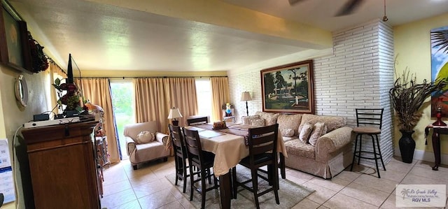 dining room featuring light tile patterned floors, brick wall, and a ceiling fan