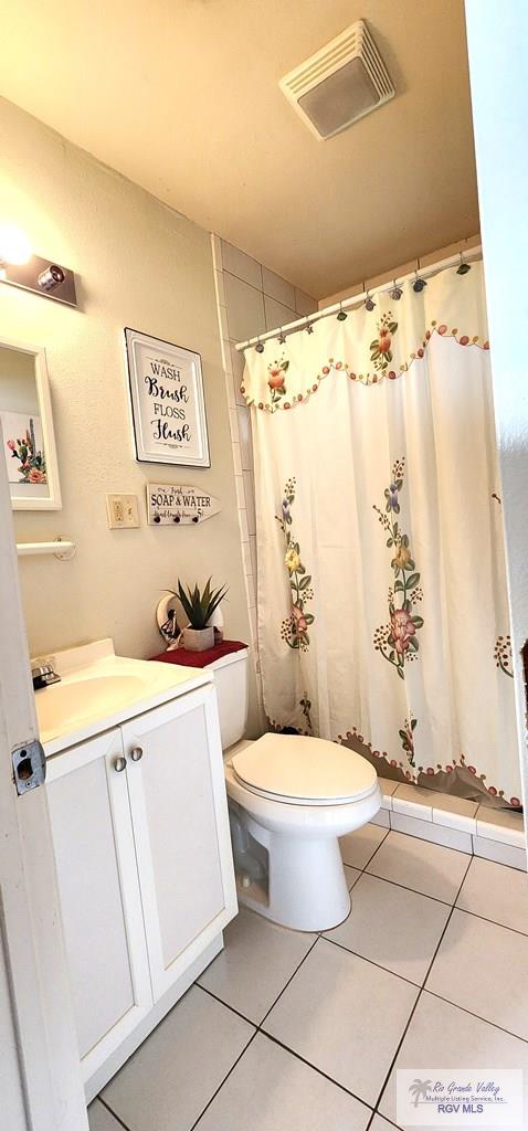 full bathroom with toilet, vanity, curtained shower, visible vents, and tile patterned floors