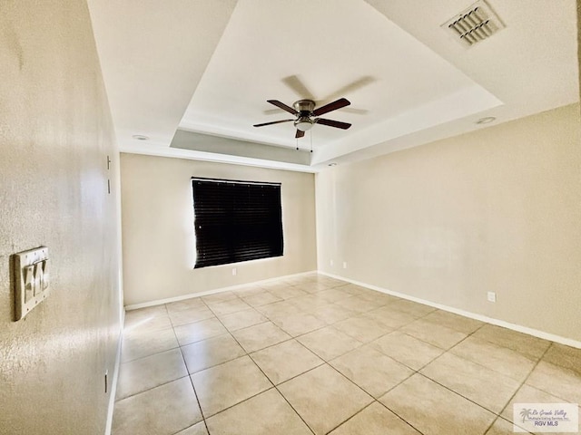 tiled spare room with a raised ceiling and ceiling fan