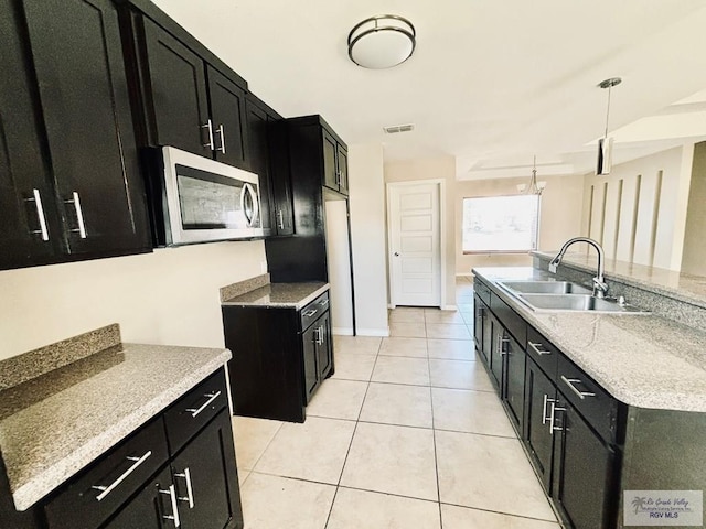 kitchen with light tile patterned flooring, an island with sink, hanging light fixtures, and sink