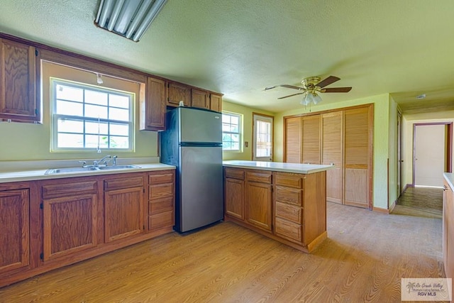 22916 N Oscar St, Harlingen, TX 78552 - kitchen with freestanding refrigerator, a peninsula, light wood-type flooring, light countertops, and a textured ceiling