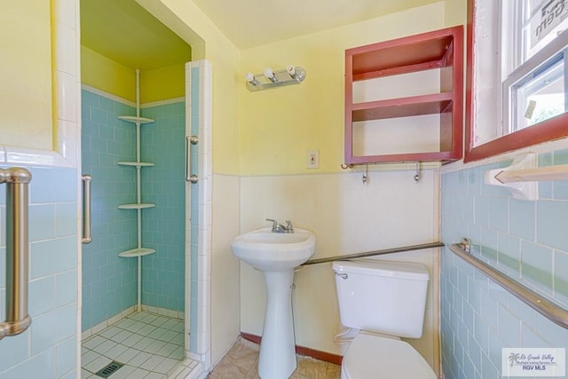 22916 N Oscar St, Harlingen, TX 78552 - bathroom with a stall shower, tile walls, tile patterned floors, and a wainscoted wall
