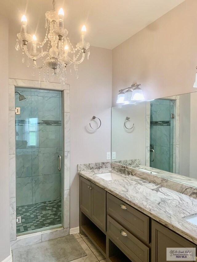 bathroom featuring tile patterned flooring, vanity, a shower with shower door, and an inviting chandelier