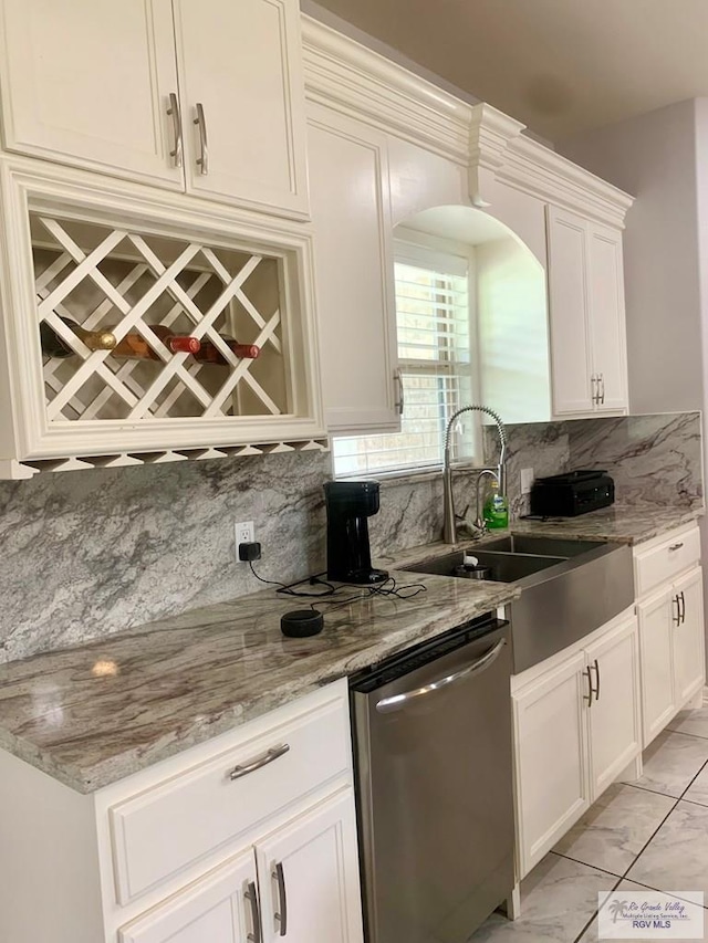 kitchen with tasteful backsplash, stainless steel dishwasher, light stone counters, sink, and white cabinetry