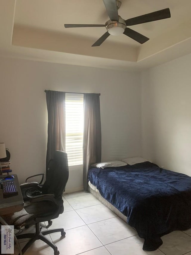 bedroom with a tray ceiling, ceiling fan, and light tile patterned flooring