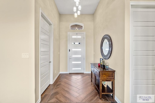 entryway featuring dark parquet flooring and an inviting chandelier