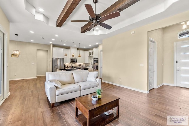 living room featuring wood-type flooring, ceiling fan, and beam ceiling