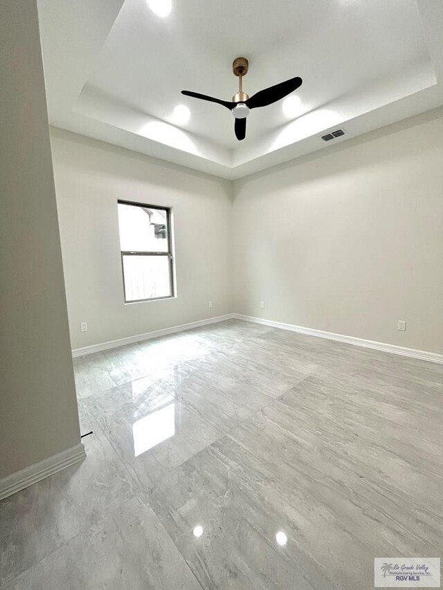 spare room featuring a tray ceiling and ceiling fan