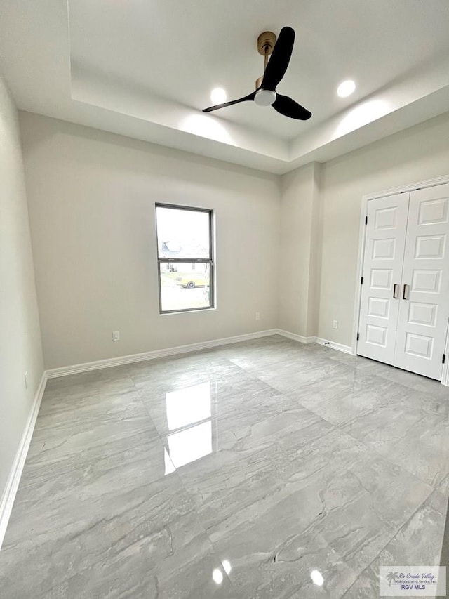 spare room with a tray ceiling and ceiling fan