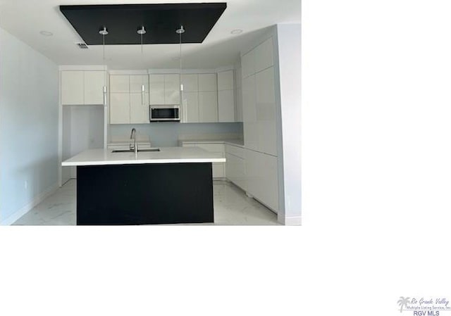 kitchen featuring sink, white cabinetry, and an island with sink