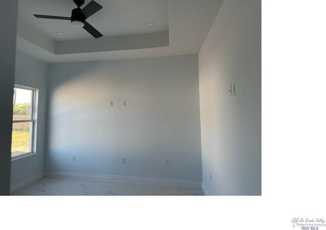 spare room featuring a raised ceiling and ceiling fan