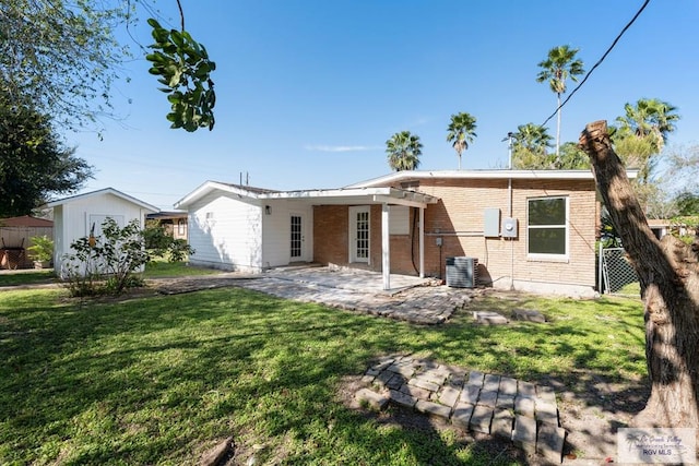 back of property with cooling unit, brick siding, fence, a lawn, and a patio area