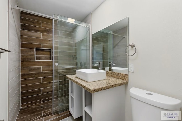 bathroom featuring toilet, a tile shower, and vanity