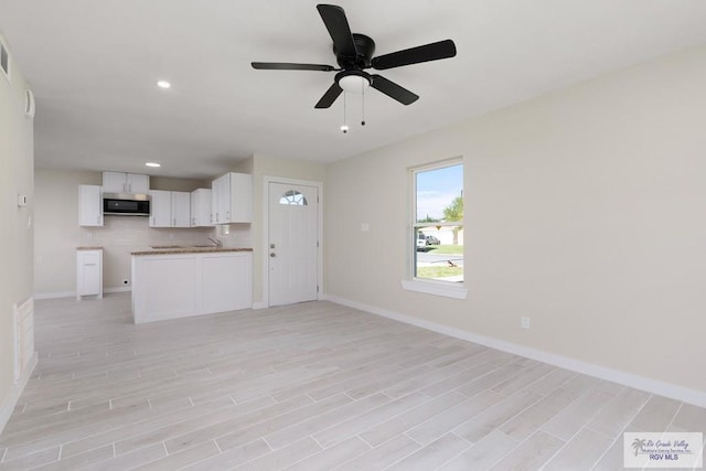 unfurnished living room with recessed lighting, a sink, a ceiling fan, baseboards, and light wood finished floors