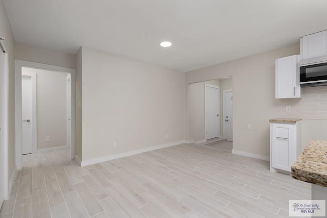 unfurnished living room with light wood-style flooring, baseboards, and recessed lighting